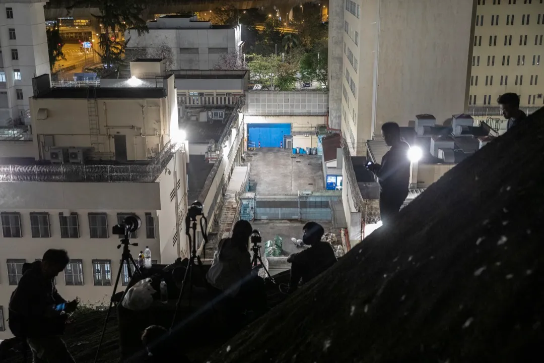 2021年3月2日凌晨，一眾攝影記者在山坡上等候拍攝被押解到荔枝角收押所的被告。攝：林振東/端傳媒