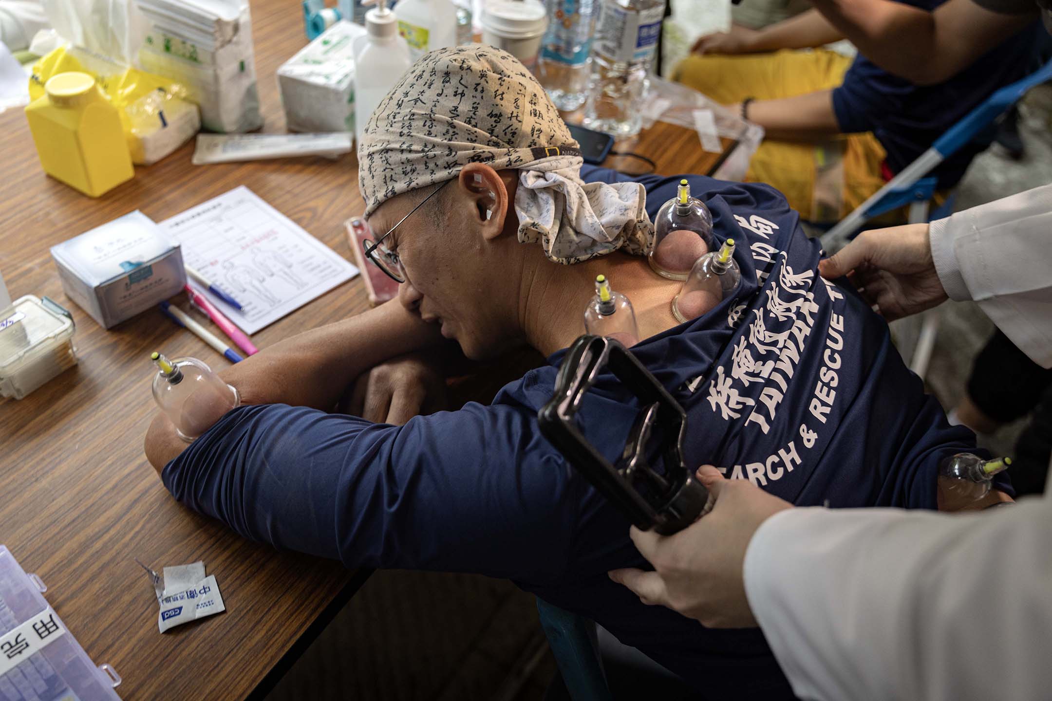 2024年4月5日，花蓮，一名醫師為疲累的救援人員拔罐。攝：陳焯煇/端傳媒