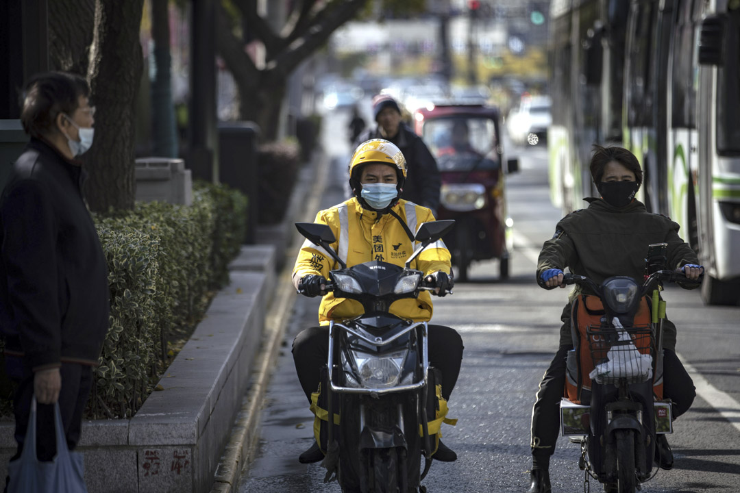 2020年11月29日，美團的送餐快遞員在上海的交通信號燈旁等候。